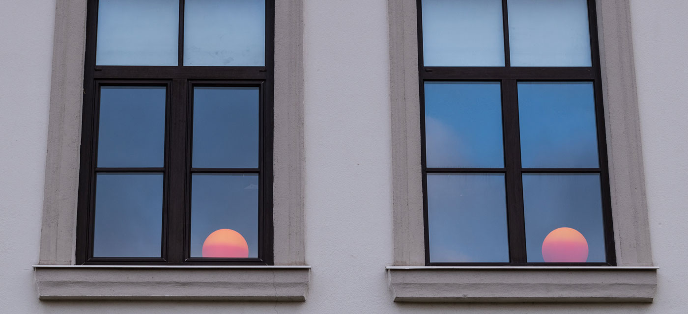 Ventanas con doble acristalamiento que muestran el reflejo del sol al atardecer, simbolizando confort y eficiencia energética.