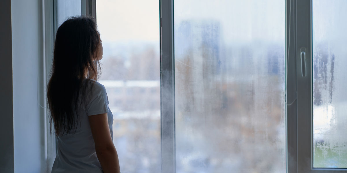 Mujer mirando por ventana con condensación - Climalit