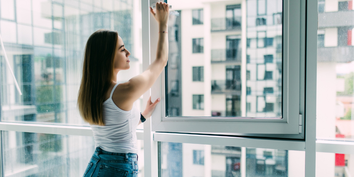 Imagen de mujer cerrando ventana Climalit en vivienda