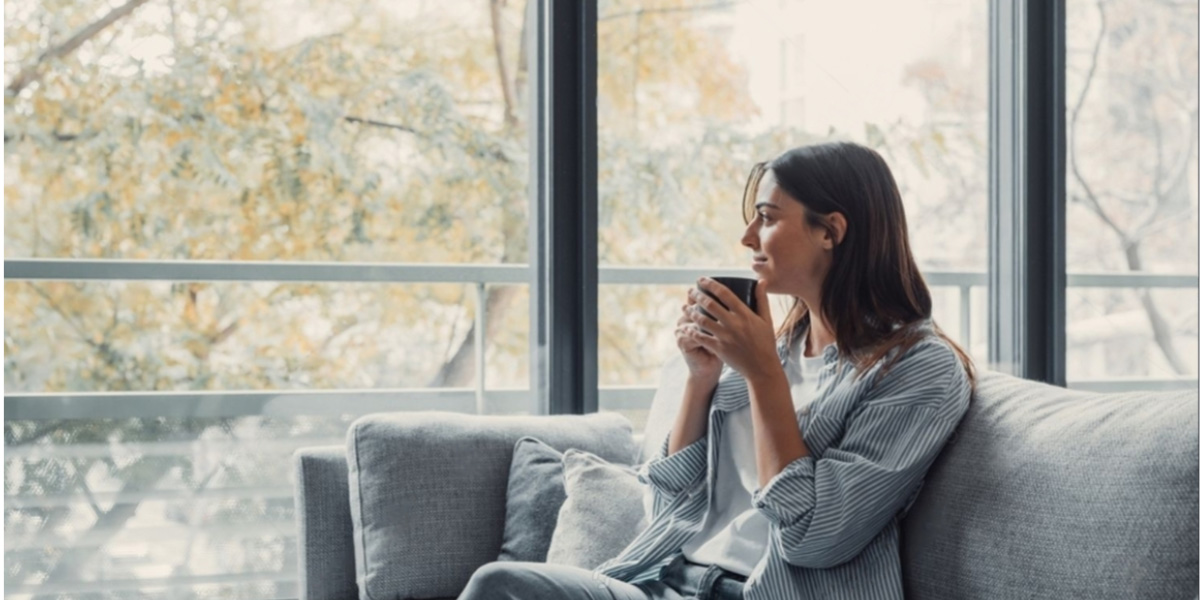 Mujer tomando taza café en sofá de su hogar Climalit