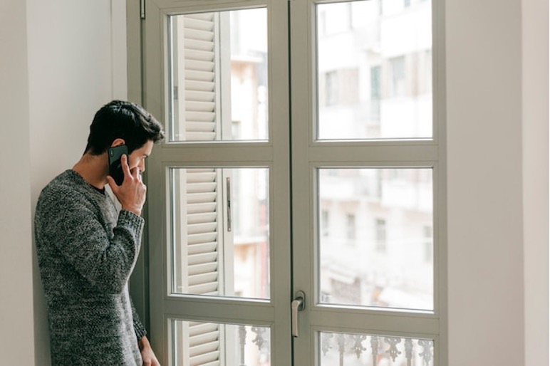 Persona hablando por teléfono mirando por la ventana, Climalit