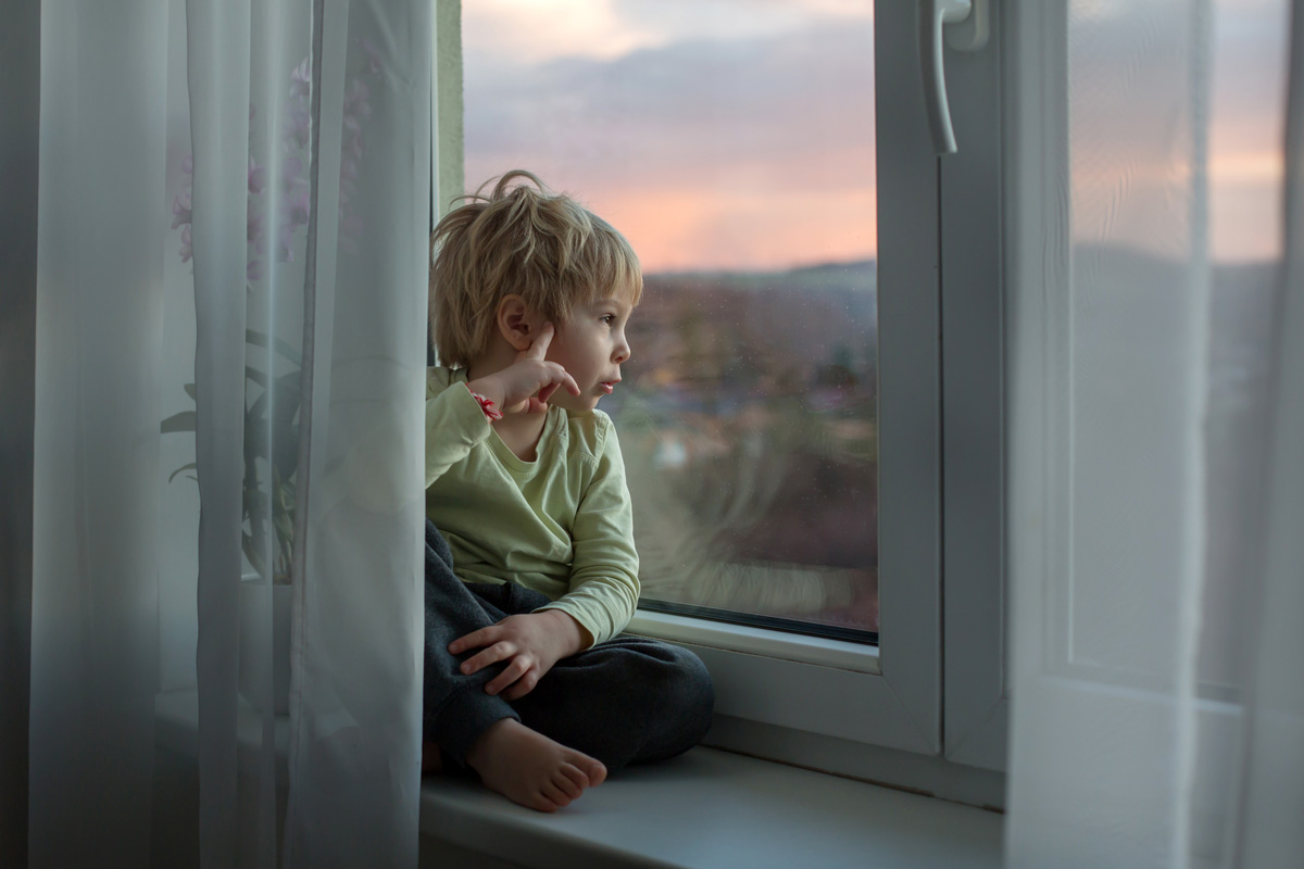 Niño sentado junto a ventana moderna con perfil seguro