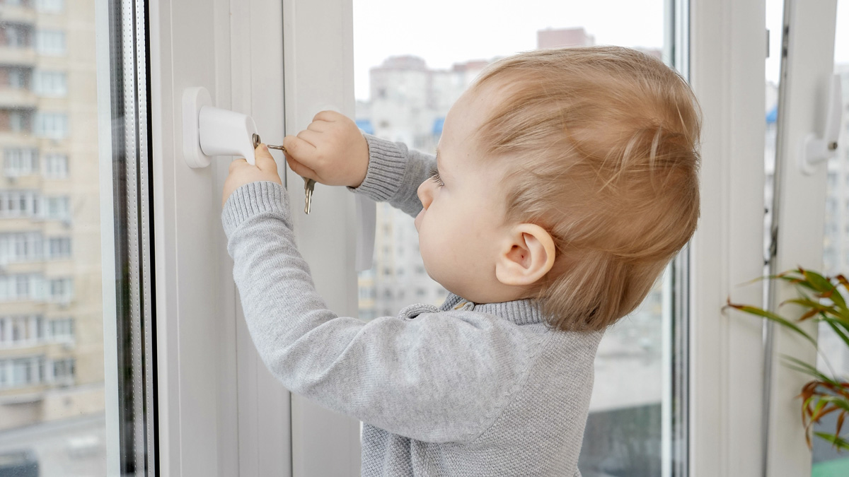 Niño usando cerradura de seguridad en ventana