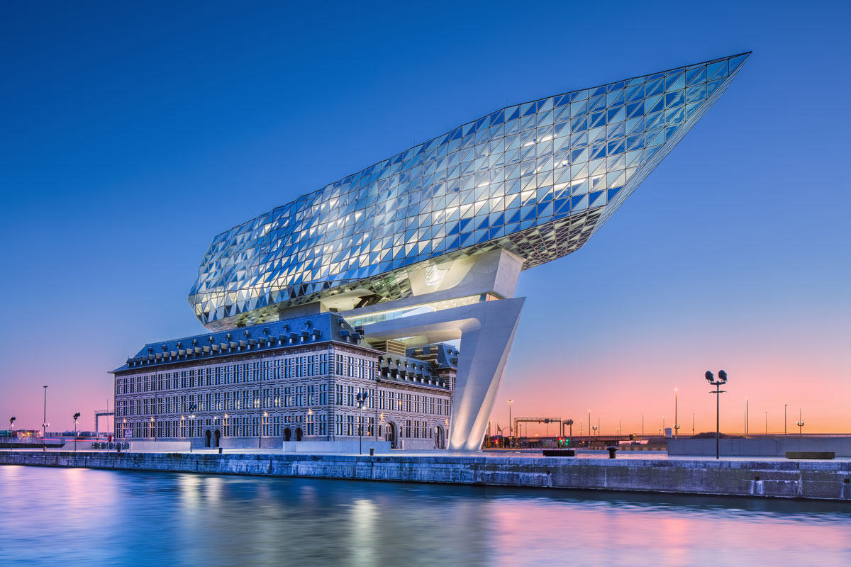 Edificio moderno con estructura de vidrio curvado sobre fachada histórica al atardecer