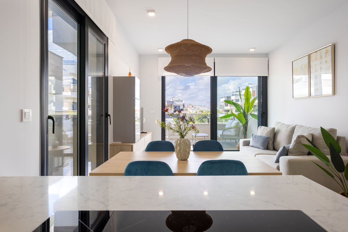 Salón con puertas acristaladas hacia terraza, donde el acristalamiento elegido según la orientación de la vivienda contribuye a mejorar el aislamiento térmico, la eficiencia energética y el bienestar interior.